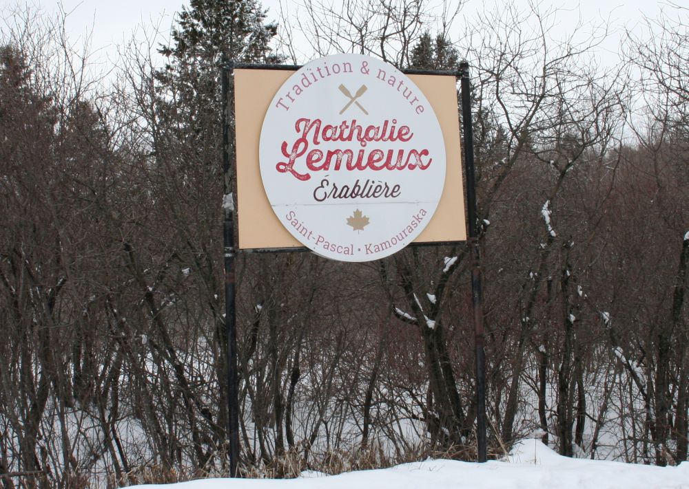 Beige sign with brown border and central white ellipse bearing the inscription.
